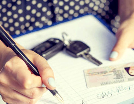 Persona rellenando documentación con carnet de conducir y llaves de coche