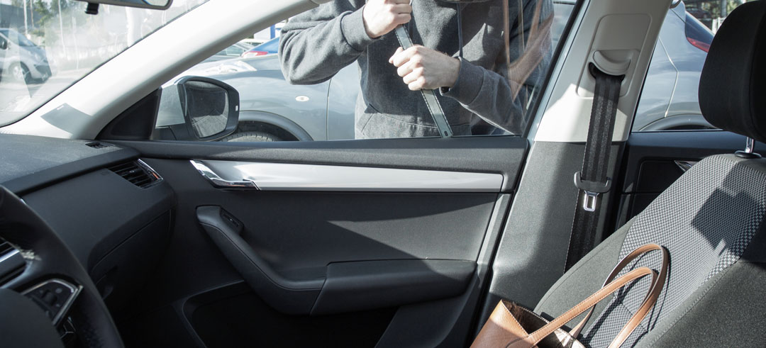 Persona intentado abrir la ventana de un coche para conseguir un bolso
