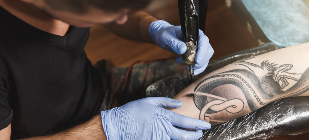Tatuador mientras tatúa un brazo